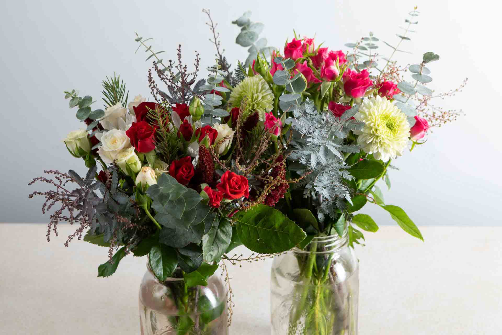 two holiday arrangements of flowers