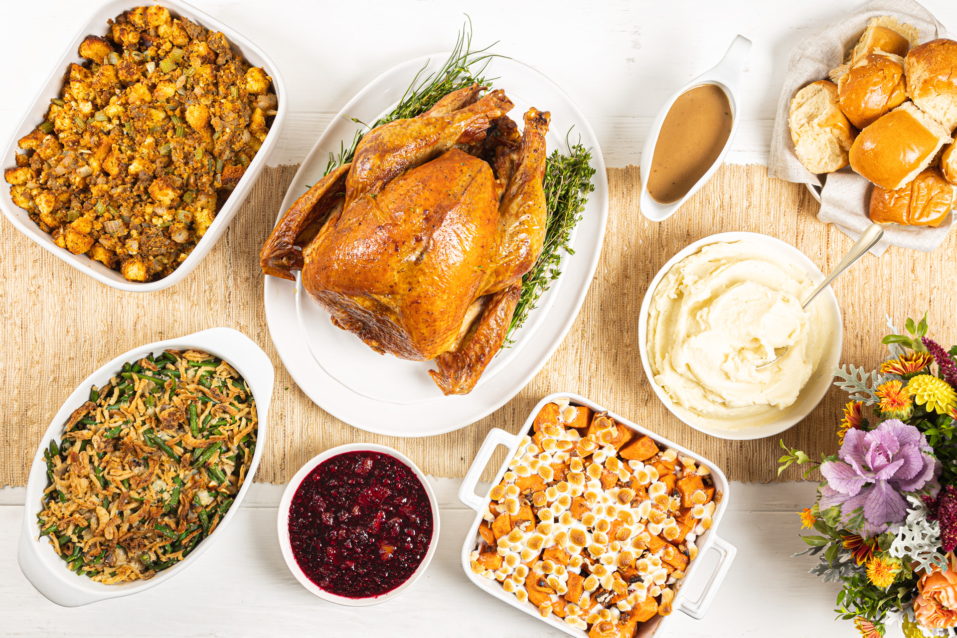 Holiday meal with roasted turkey, stuffing, mashed potatoes, green bean casserole, sweet potato casserole, rolls and cranberry sauce